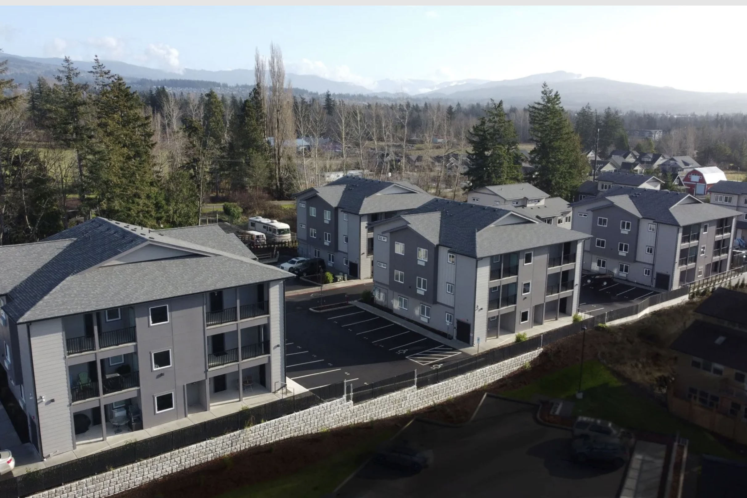 Aerial view of multifamily buildings and their parking area.